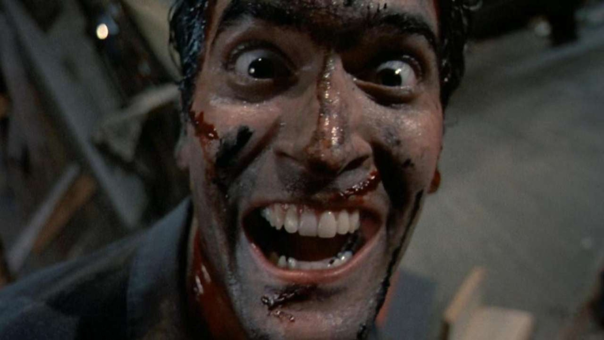'Evil Dead II' Bruce Campbell as Ash Williams looking into the camera with his mouth open, and blood on his face.