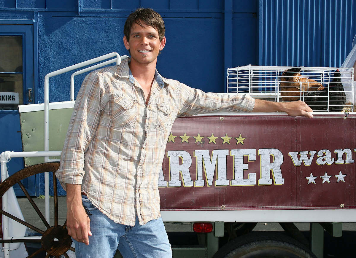 Matt Neustadt poses with a tractor in a promo shot for the 2008 CW series 'Farmer Wants a Wife'