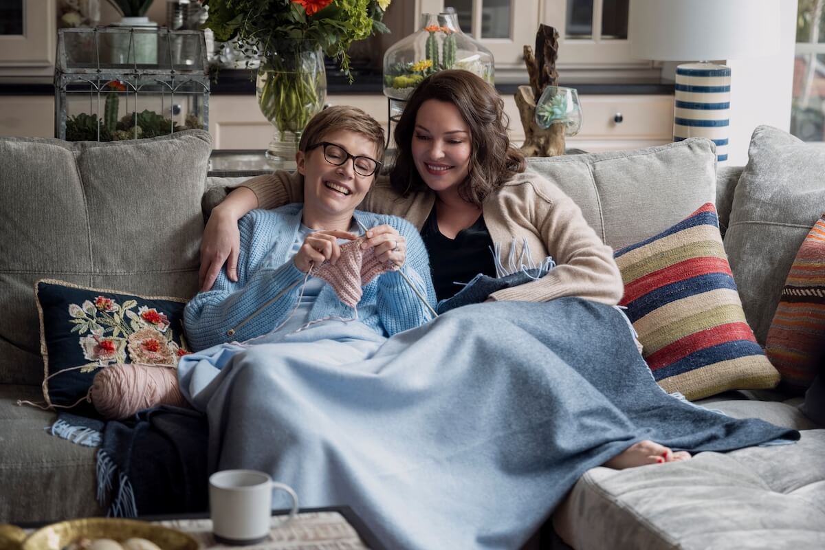 Kate (Sarah Chalke) and Tully (Katherine Heigl) sitting on a couch in 'Firefly Lane' Season 2 Part 2