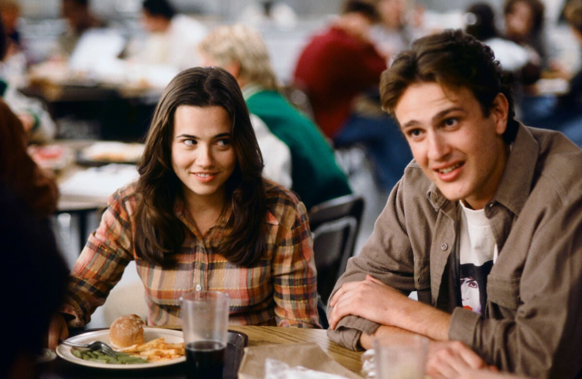 Linda Cardellini and Jason Segel cast members sitting next to each other in a scene in 'Freaks and Geeks'