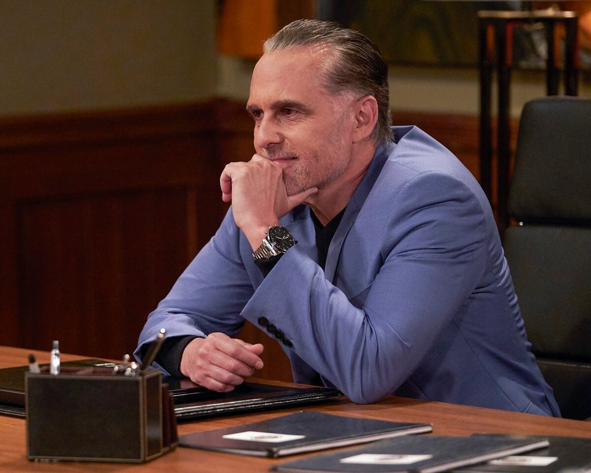 'General Hospital' star Maurice Benard dressed in a blue suit, sitting at a desk in a soap opera scene.