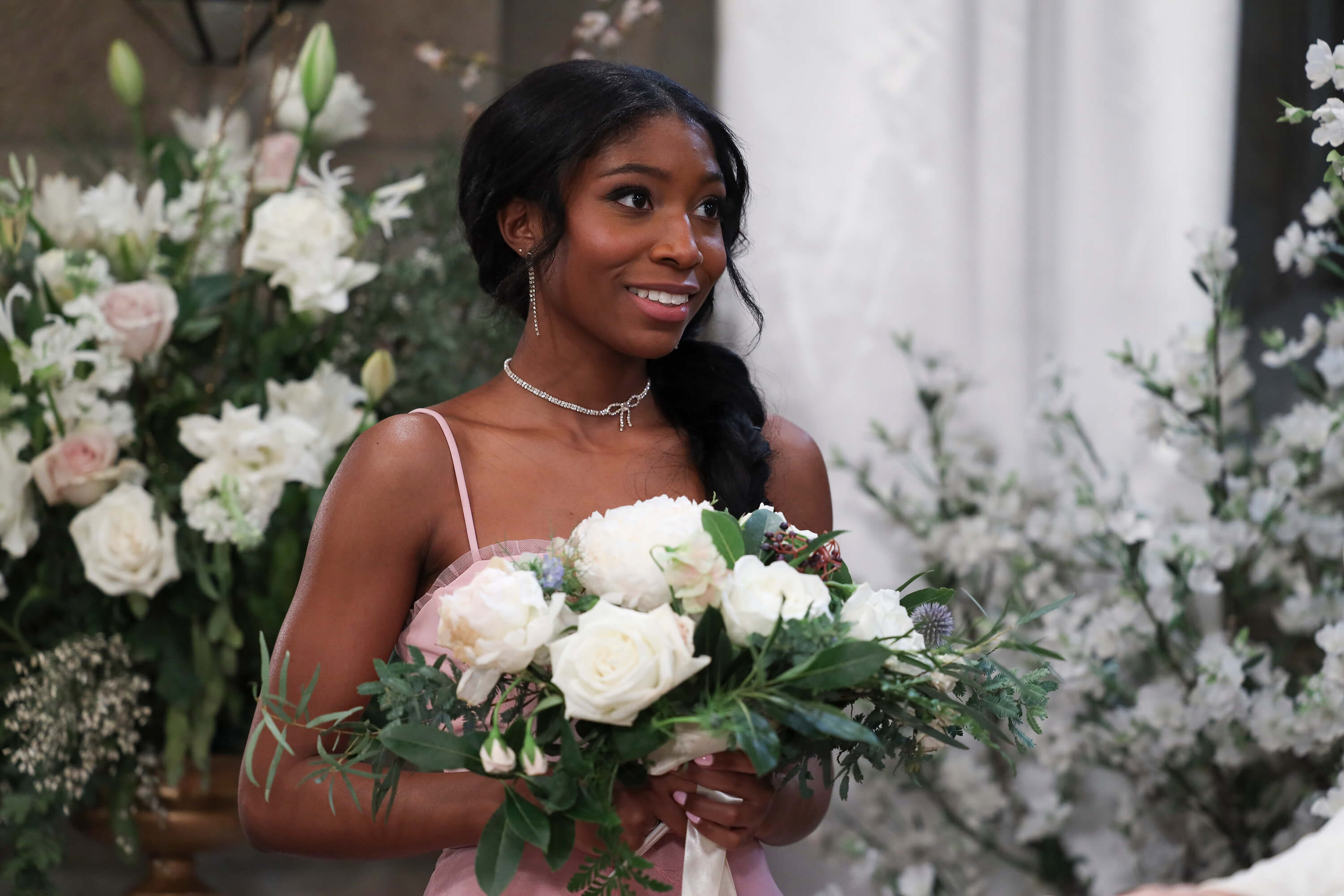 'General Hospital' star Tabyana Ali in a pink dress, holds a bouquet of flowers.