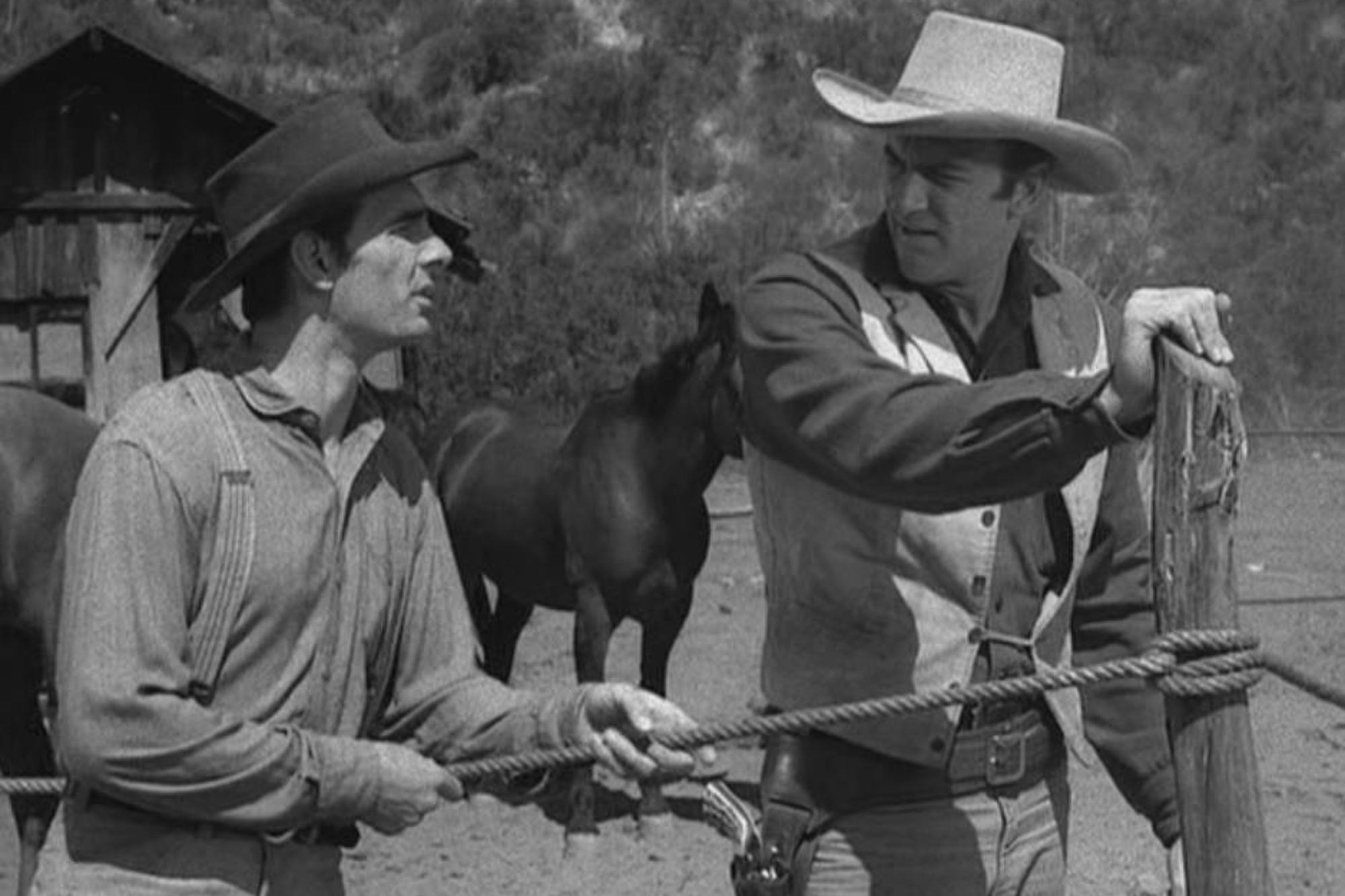 'Gunsmoke' Dennis Weaver as Chester Goode and James Arness as Matt Dillon. Chester is holding onto a rope, while Matt is holding onto the post, looking at him.
