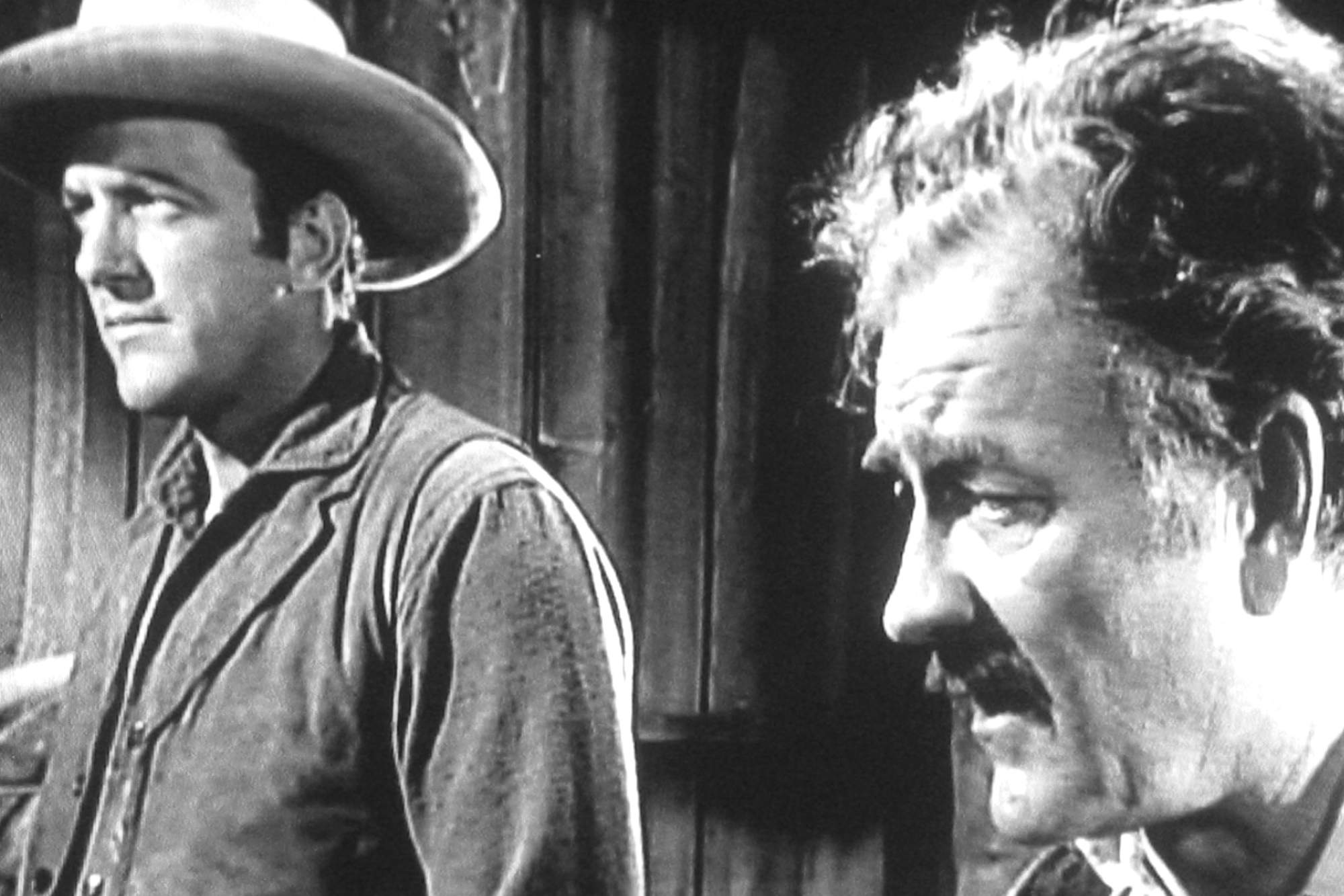 'Gunsmoke' James Arness as Matt Dillon and Milburn Stone as Doc Adams standing next to each other with a serious look on their faces.