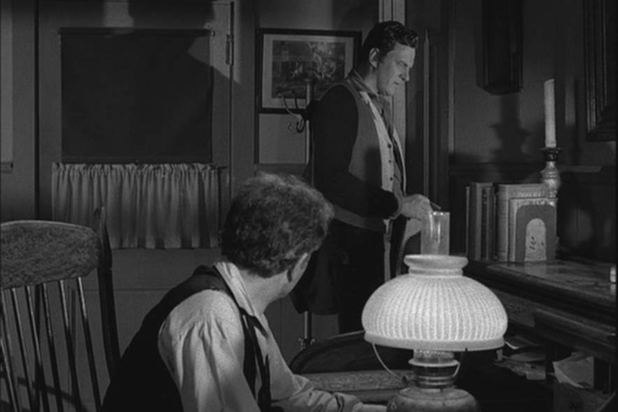 'Gunsmoke' Milburn Stone as Doc Adams and James Arness as Matt Dillon. Doc is sitting down at the desk and Matt is standing, looking off.