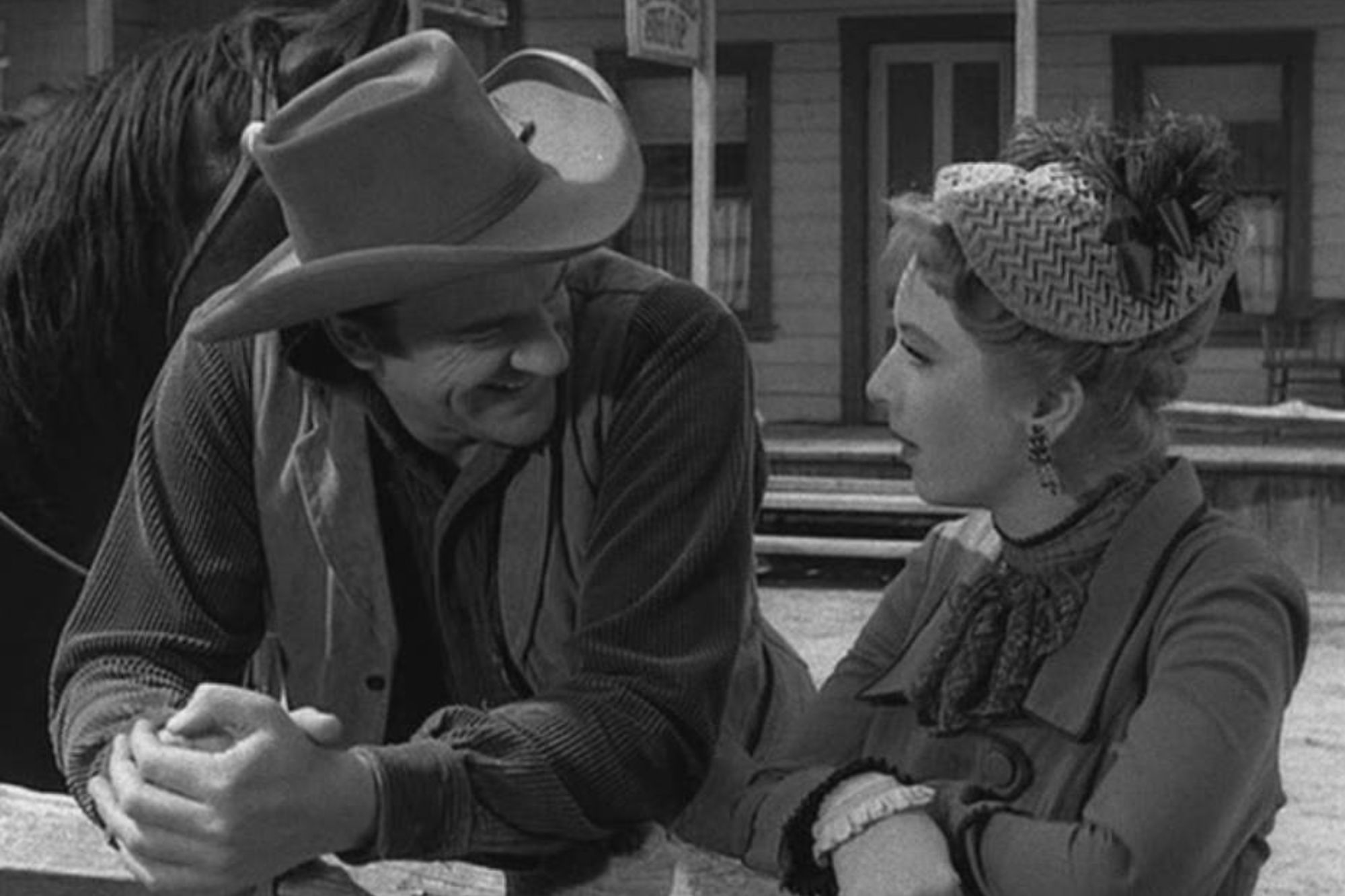 'Gunsmoke' Season 3 episodes 'Crack-Up' James Arness as Matt Dillon and Amanda Blake as Miss Kitty Russell. They're wearing Western costumes, leaning against a fence. A horse stands behind Matt.