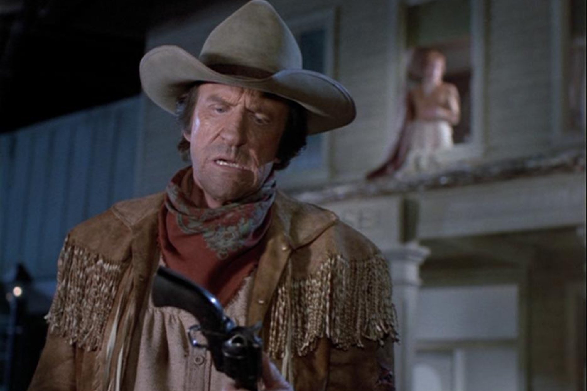'Gunsmoke: Return to Dodge' movies James Arness as Matt Dillon and Amanda Blake as Kitty Russell. He's holding his pistol, looking down at it, while she's in the background in the window.