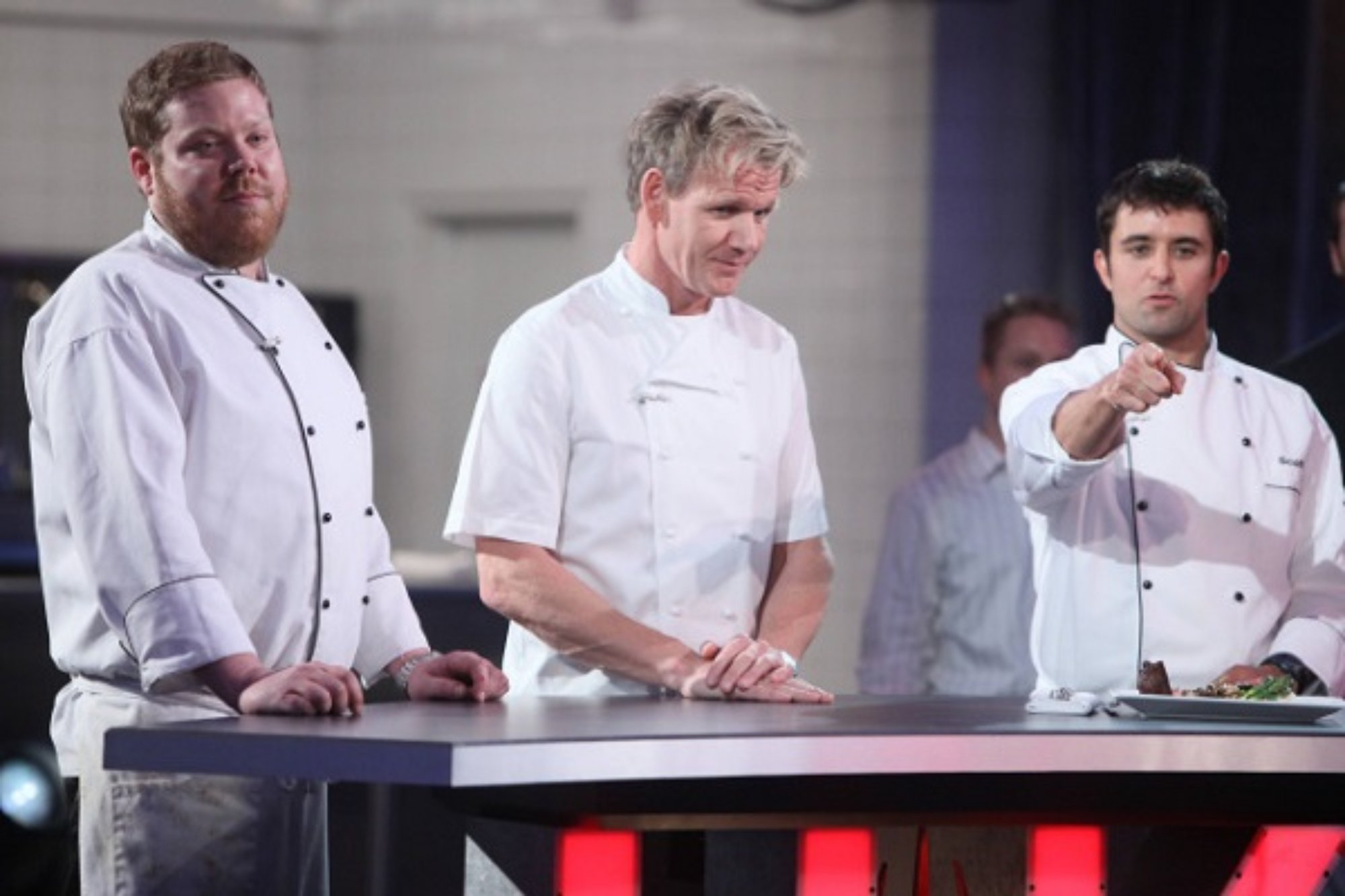 'Hell's Kitchen' Season 12 Jason Zepaltas, Gordon Ramsay, and Scott Commings picking final brigade standing behind a desk. Scott holding his hand out, pointing.