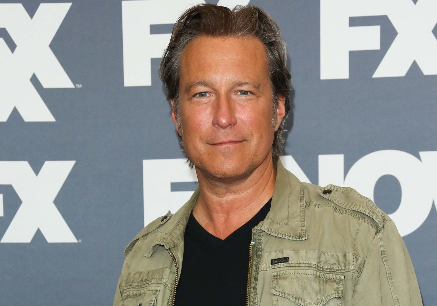 John Corbett, who stars as Robert in 'How I Met Your Father' Season 2, wears an olive green jacket over a black shirt.