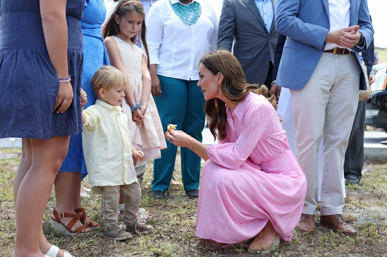 Kate Middleton kneels down and talks to a young boy.