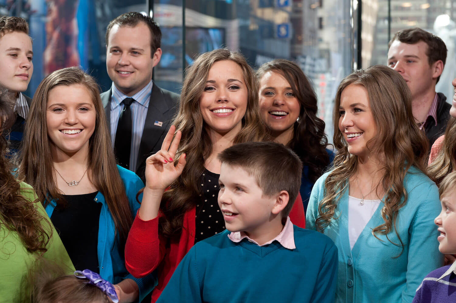 Jessa Duggar holding up a peace sign while surrounded by the Duggar family