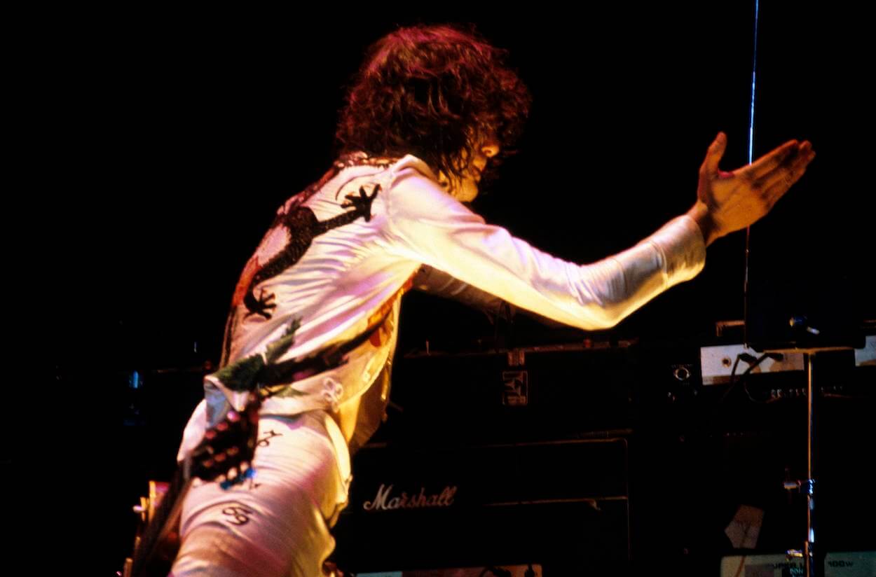 Led Zeppelin guitarist Jimmy Page wears a white outfit while playing a theremin during a 1977 concert.