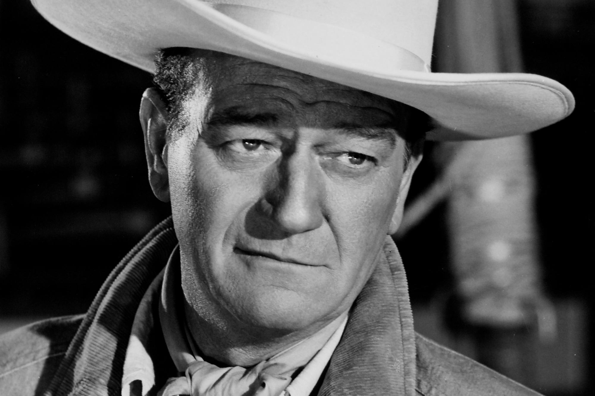 John Wayne movie 'Circus World' wearing a white cowboy hat with a slight smile on his face.