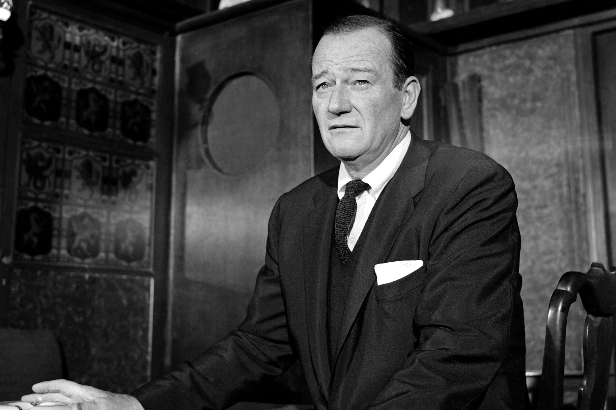 John Wayne, who had an iconic walk sitting at a table in a club wearing a suit.