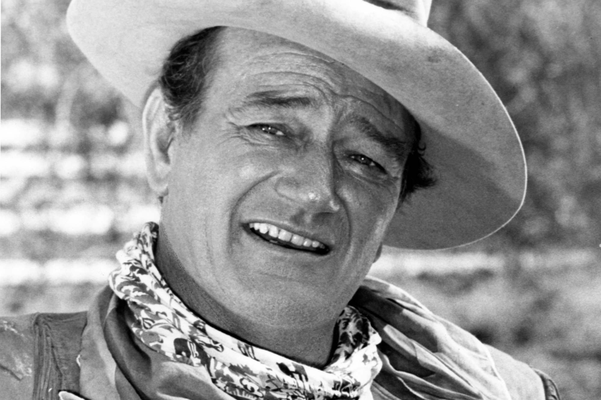 John Wayne, who starred in Westerns. A black-and-white picture with Wayne smiling, wearing a cowboy hat.