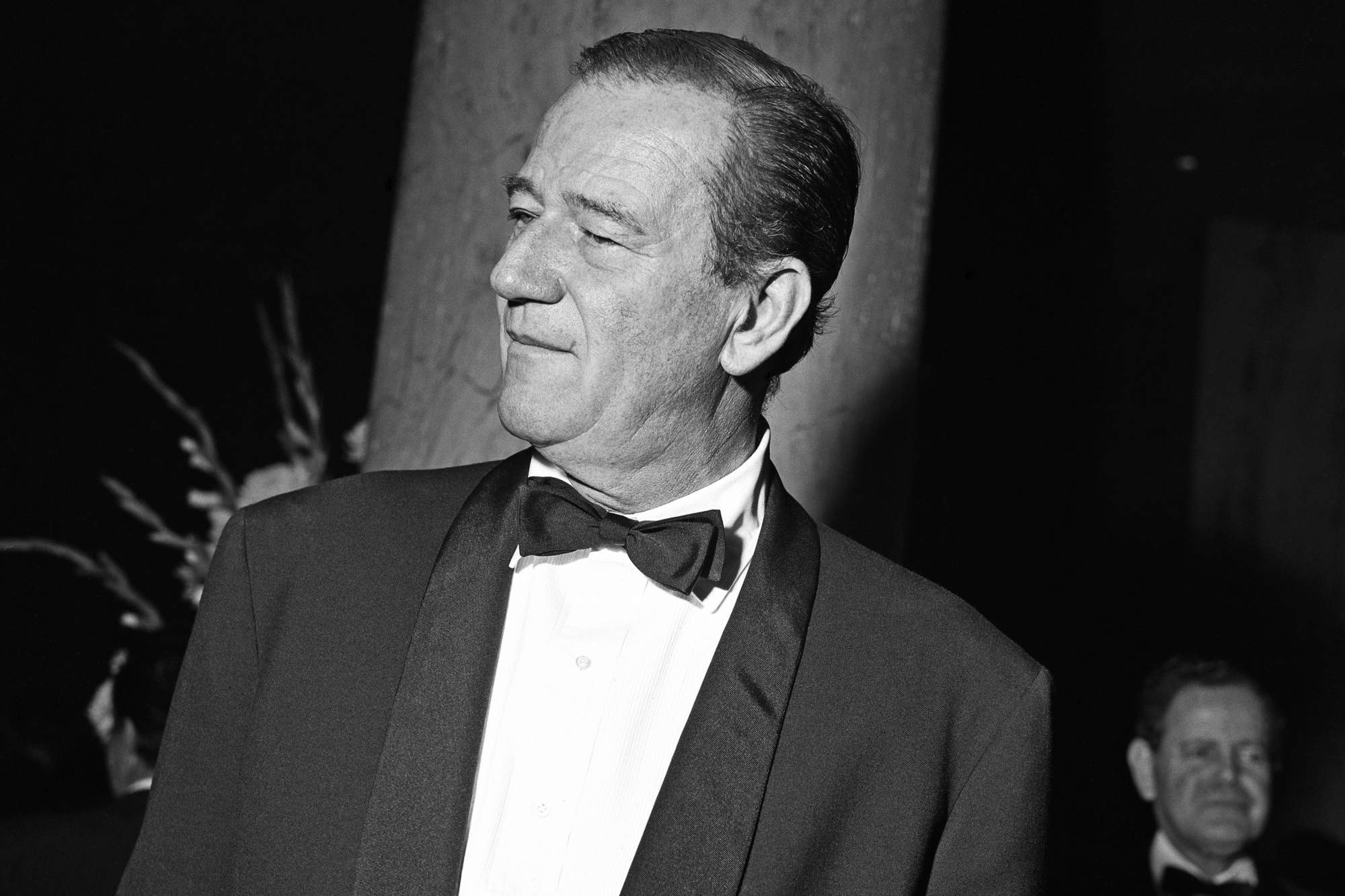 John Wayne, who was involved in a racist bit at the 1958 Oscars. He's wearing a tux in a black-and-white picture.