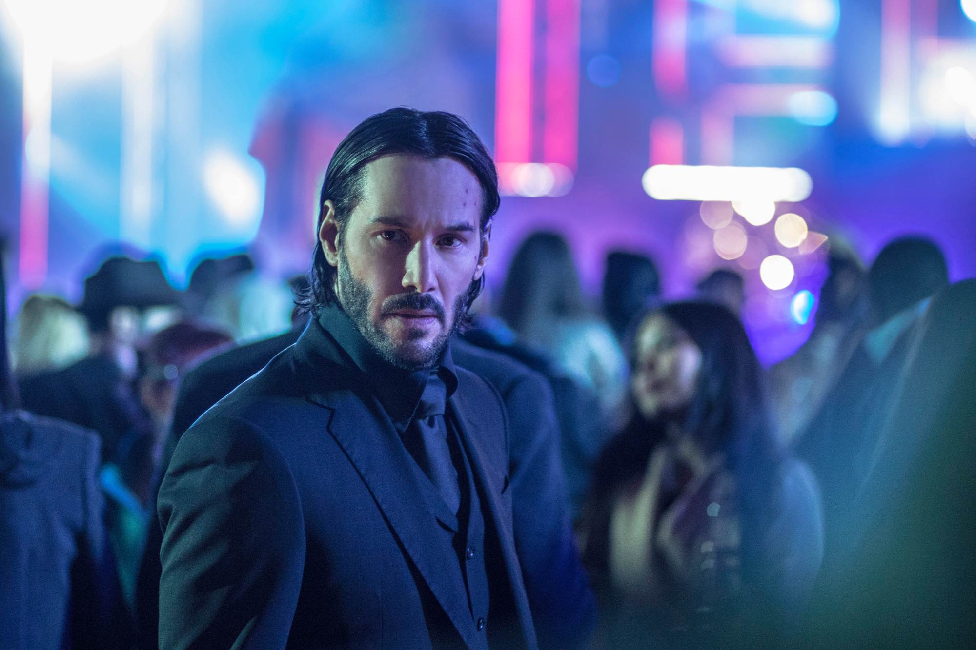 'John Wick_ Chapter 2' Keanu Reeves as John Wick standing in an all black suit in a crowd of people.