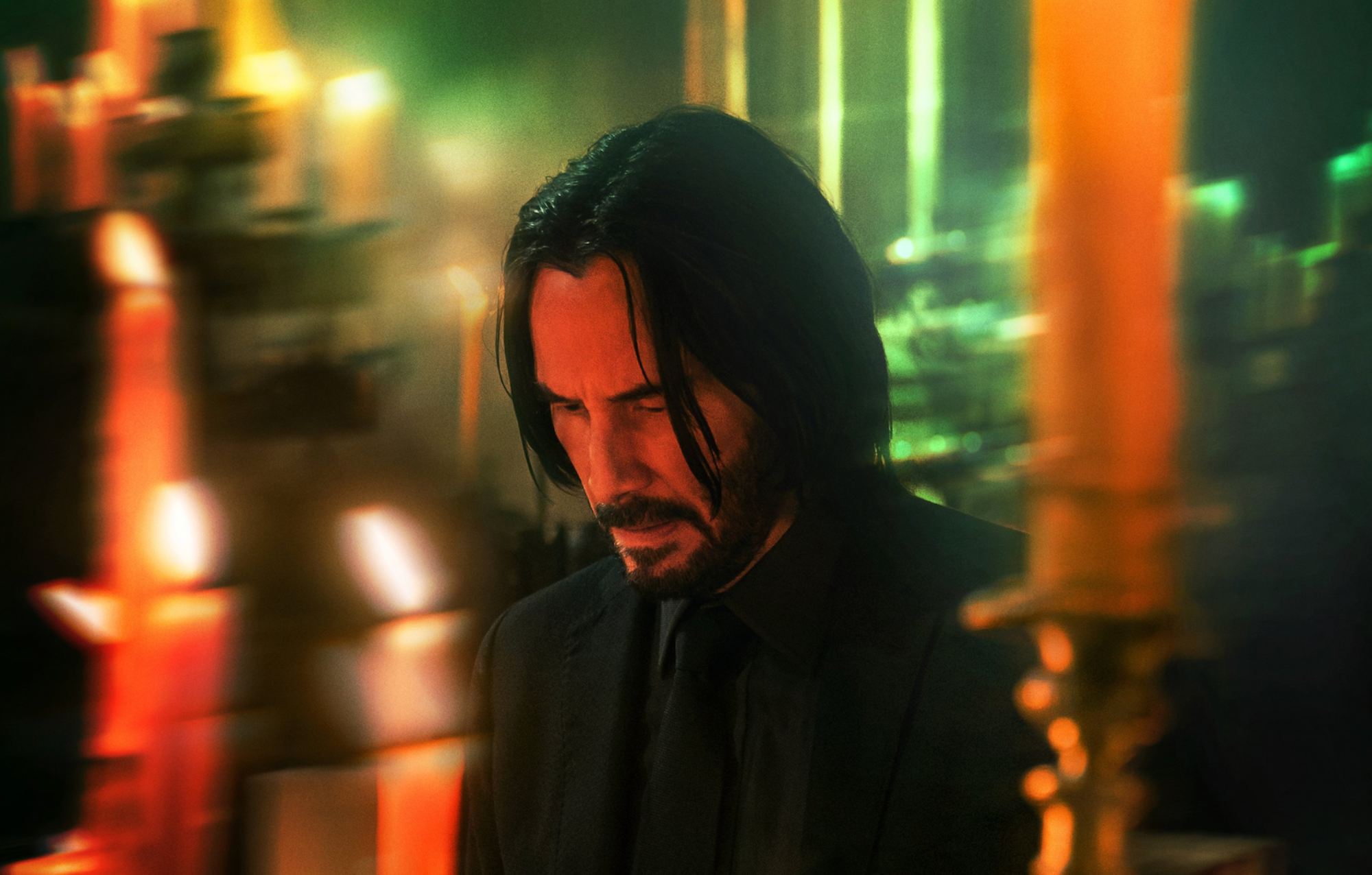 'John Wick: Chapter 4' Keanu Reeves as John Wick with his head hang low, surrounded by candles.
