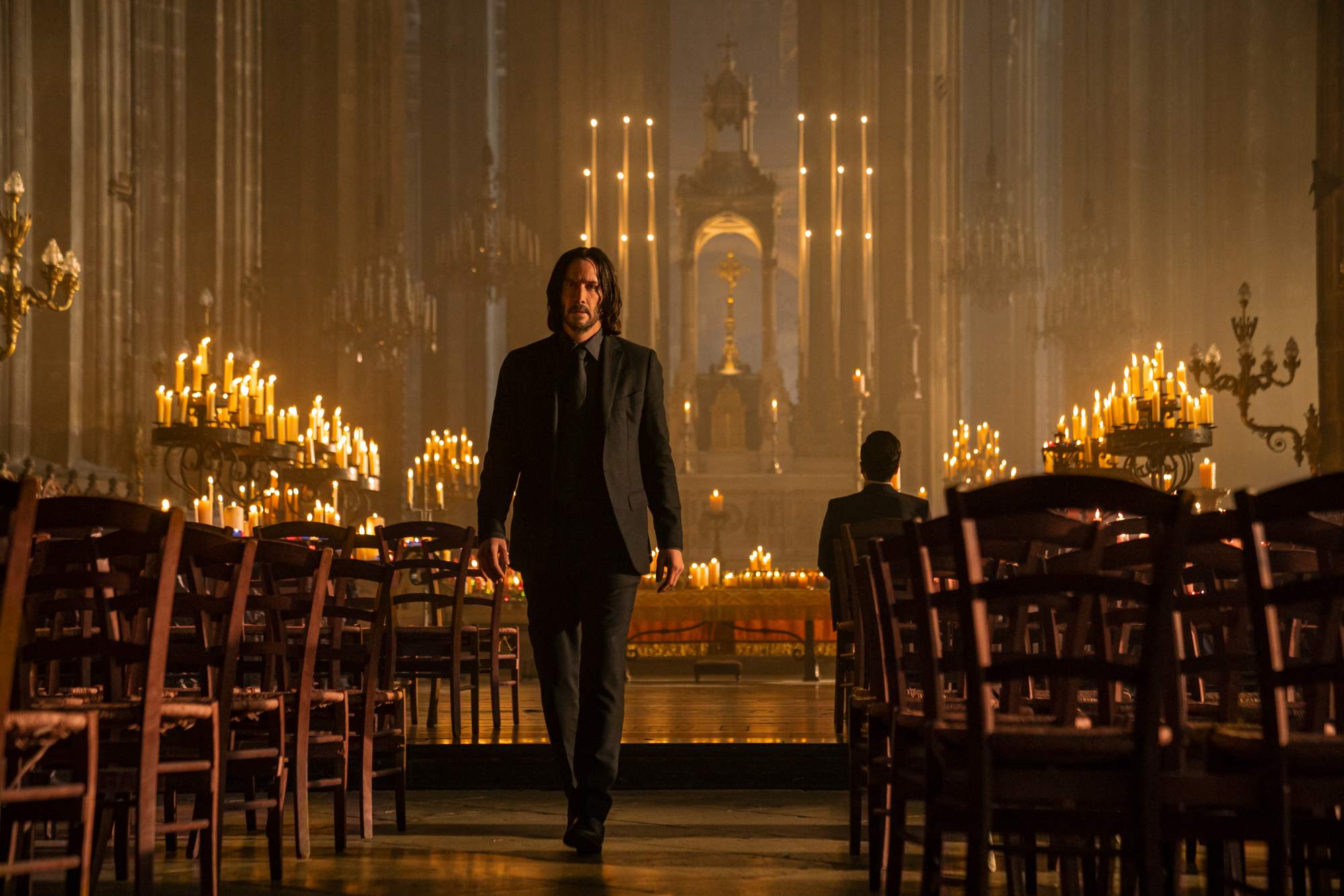 'John Wick: Chapter 4' Keanu Reeves as John Wick walking in a church with the background covered in lit candles