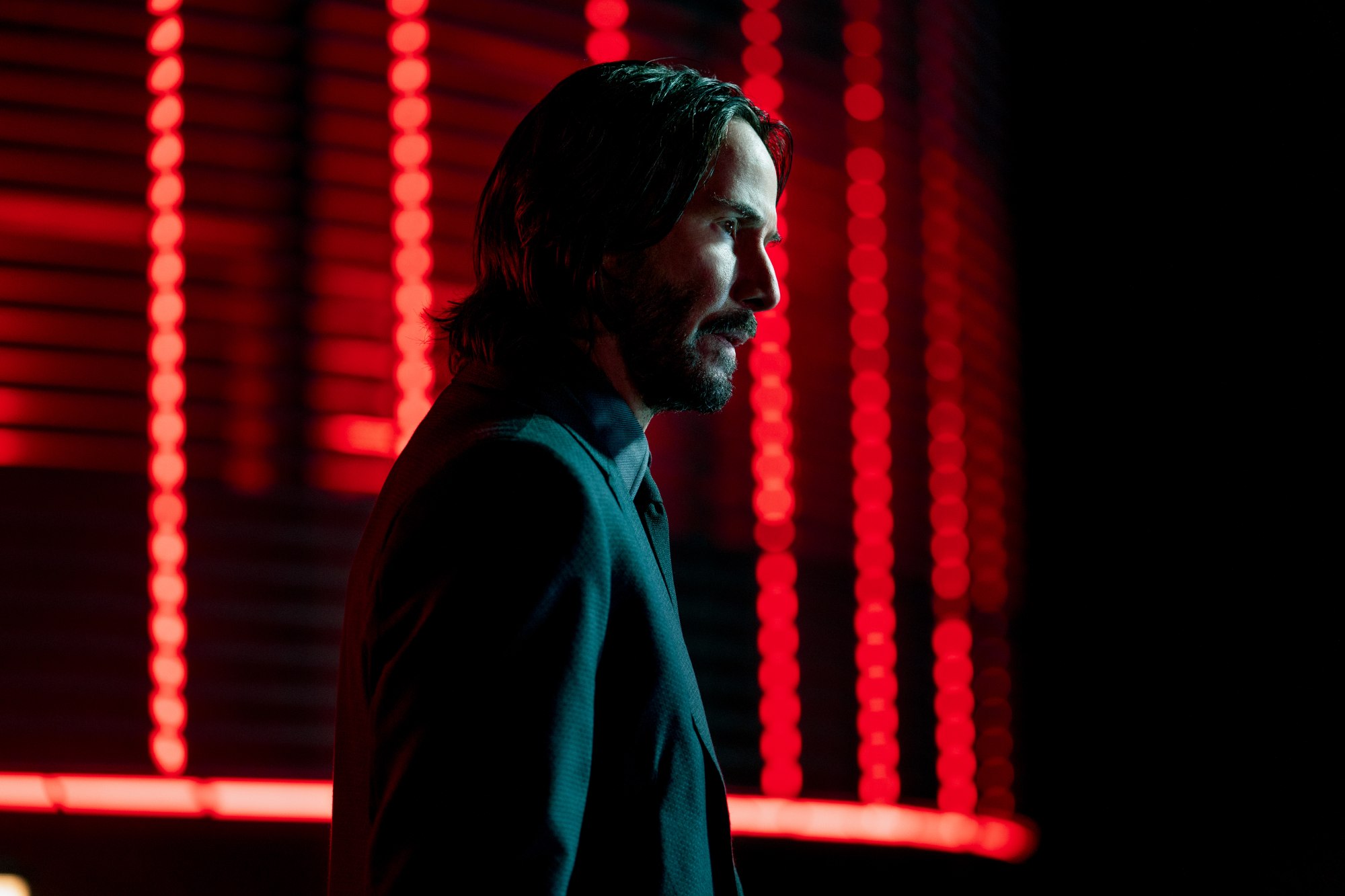 'John Wick: Chapter 4' Keanu Reeves as John Wick standing in front of neon red lighting.