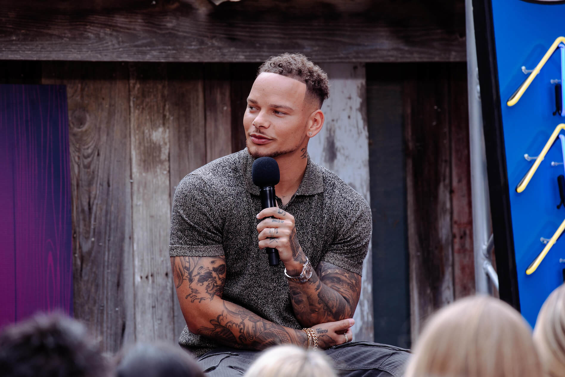 Country music singer Kane Brown holding a microphone while speaking. Kane Brown bought a house near Nashville, Tennessee