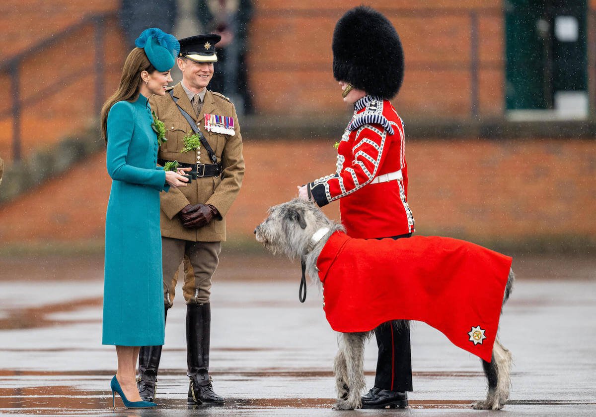 Kate Middleton smiling at a member of the King's Guard, who is escorting a dog