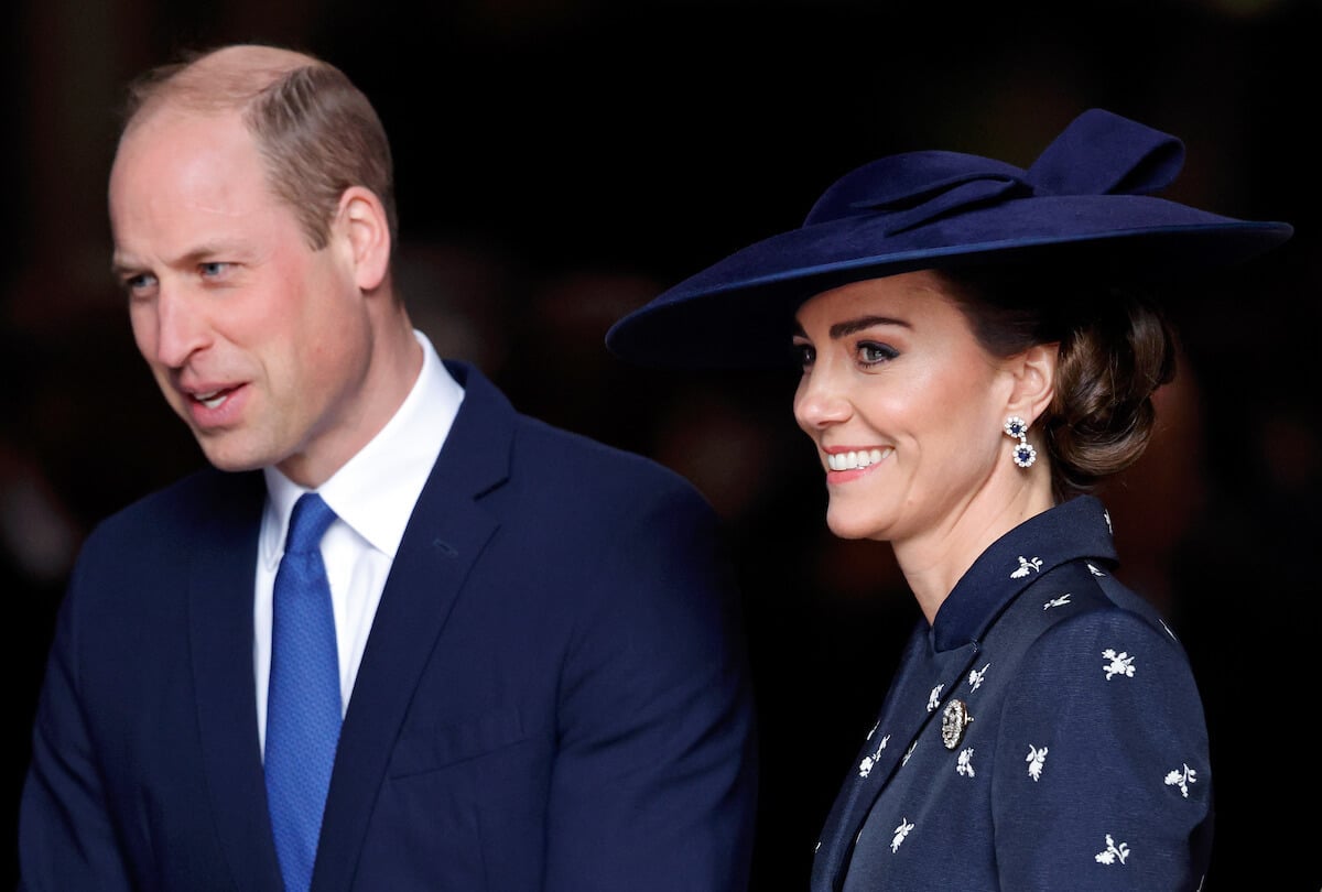 Kate Middleton and Prince William smiling, wearing complementary navy suits