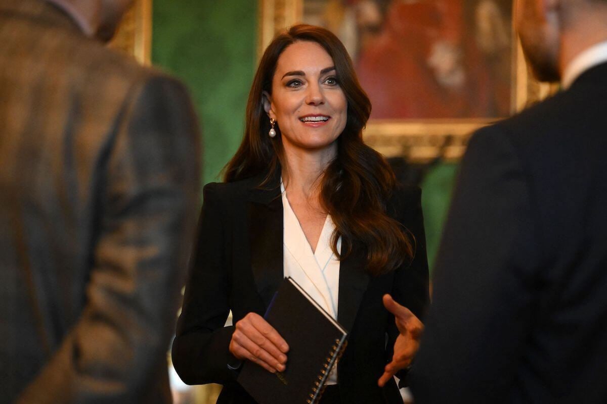 Kate Middleton looks on wearing a black pantsuit