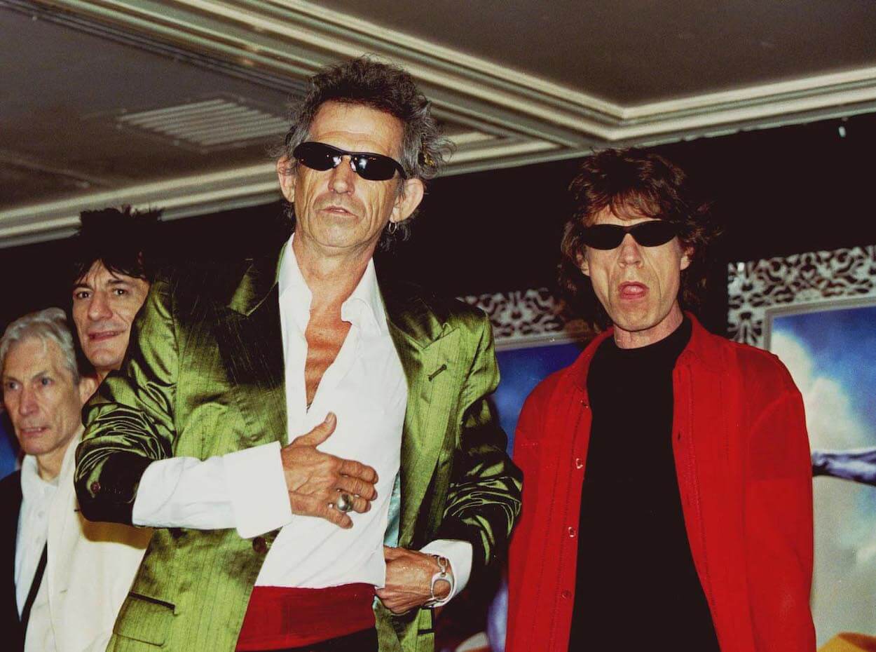 Keith Richards (front) of The Rolling Stones wears a green suit jacket as band members Charlie Watts, Ronnie Wood, and Mick Jagger look on.