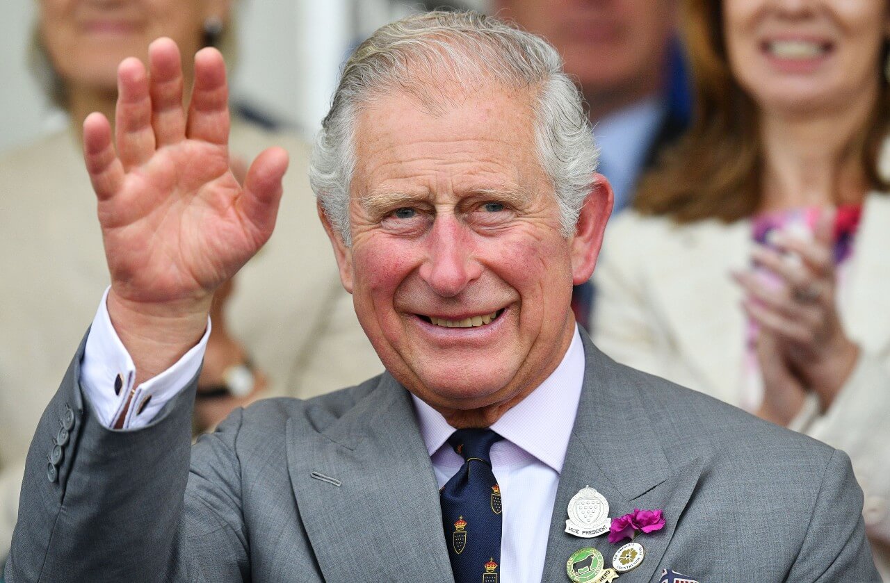 King Charles smiles and waves during an event.