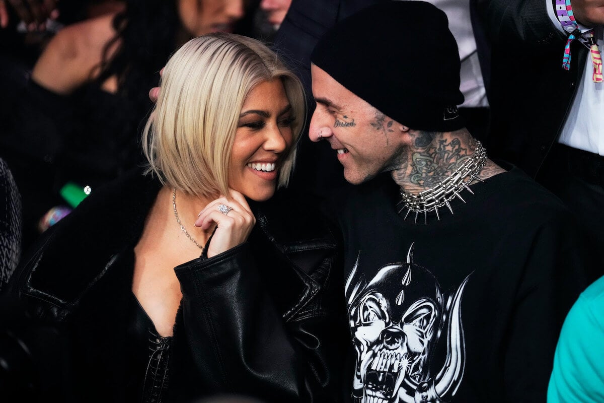 Kourtney Kardashian and Travis Barker smiling, facing each other