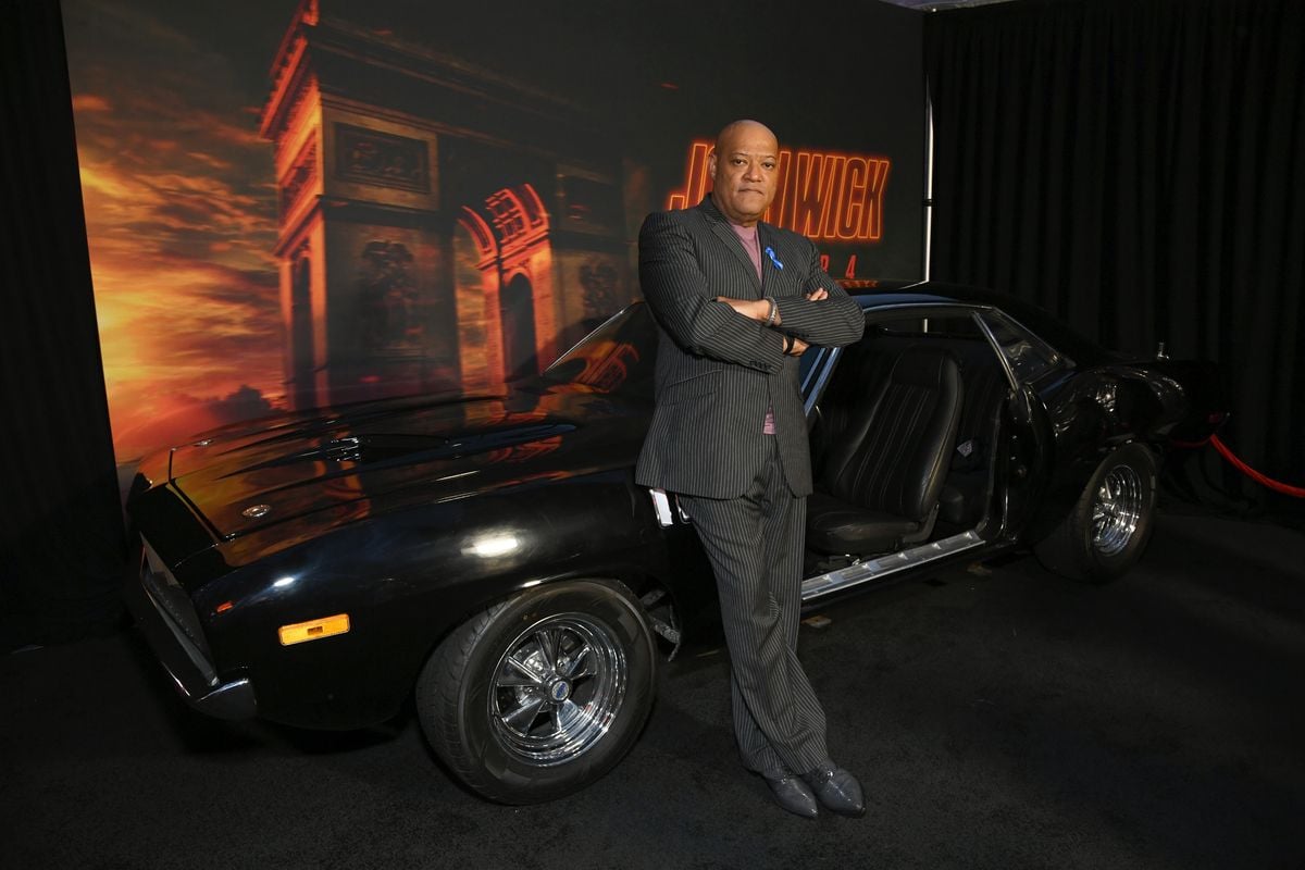 Laurence Fishburne poses in front of a prop vehicle at the premiere of "John Wick: Chapter 4"