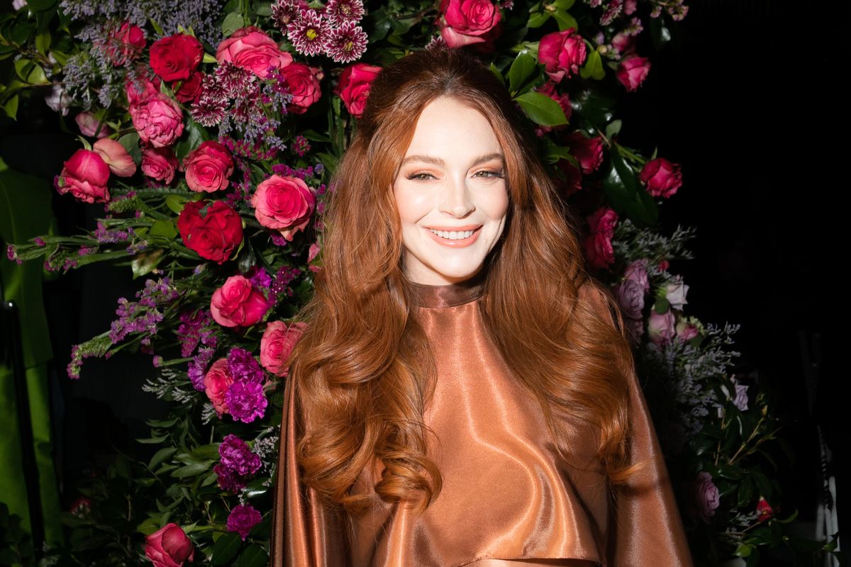 Lindsay Lohan poses in front of a bouquet of flowers.
