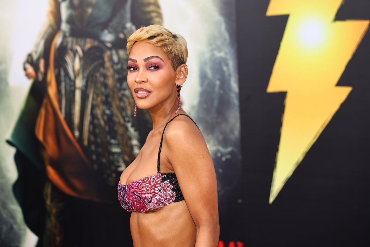 Meagan Good poses in front of key art for "Shazam! Fury of the Gods"