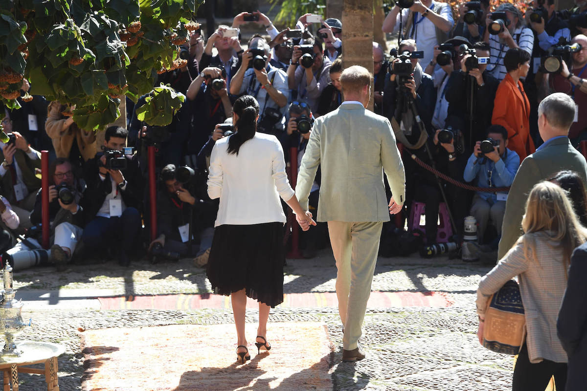 Meghan Markle and Prince Harry, whom an author says should 'back off' the British media, walk by press