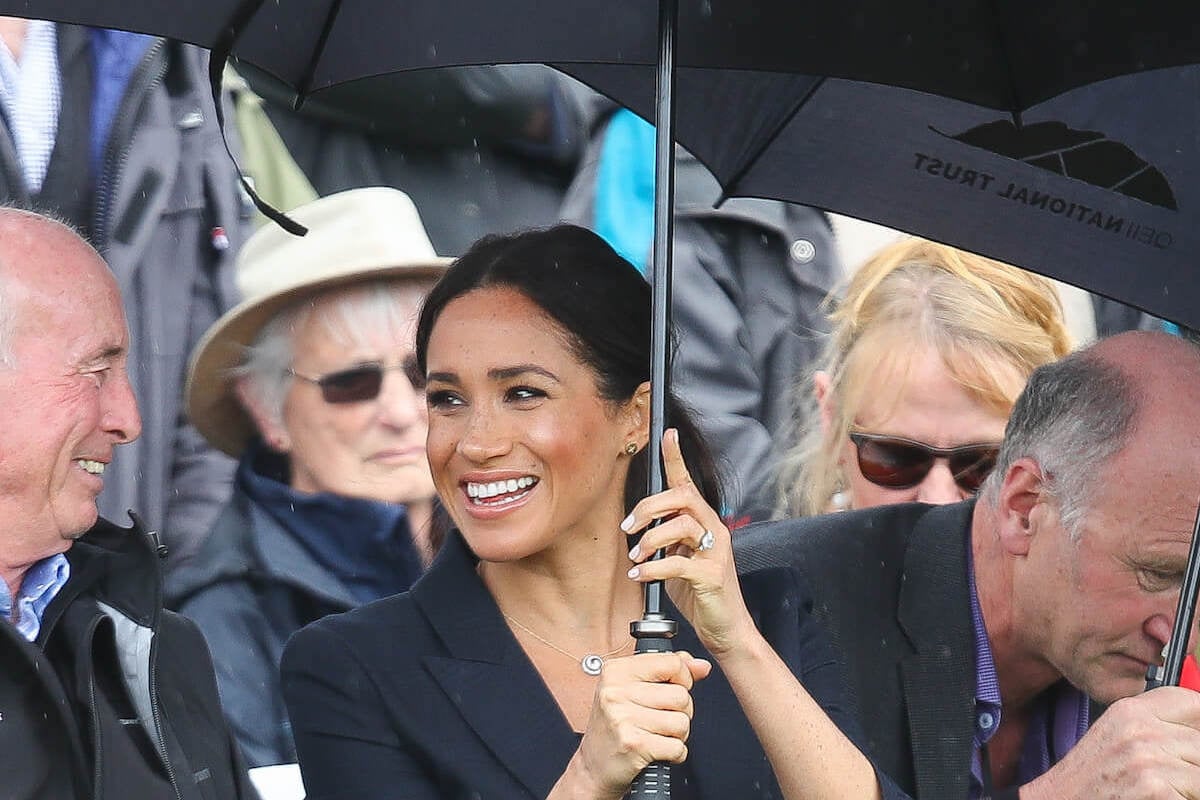 Meghan Markle smiles holding an umbrella during a 2018 royal tour