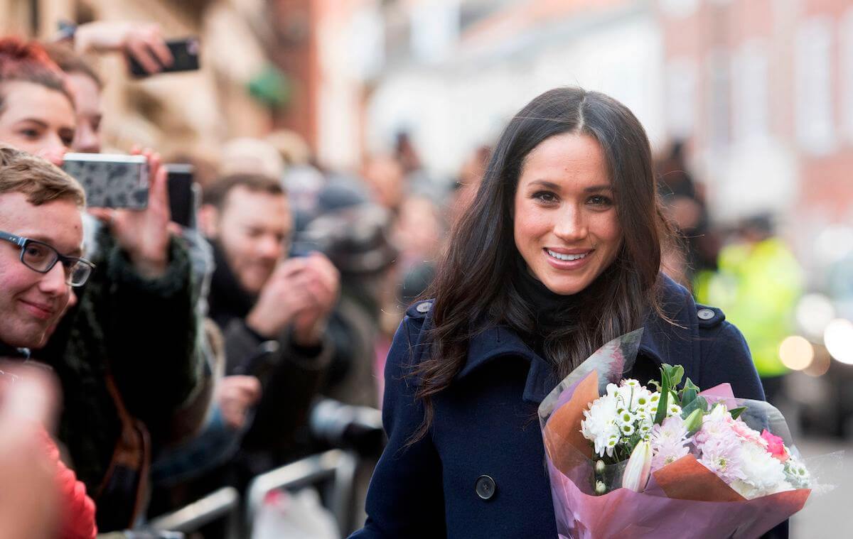 Meghan Markle, whose first walkabout in 2017 included a broken zipper wardrobe malfunction, holds flowers