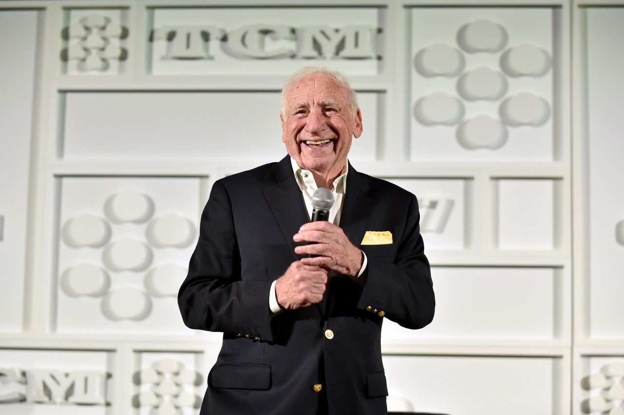Mel Brooks holds a microphone during an event.