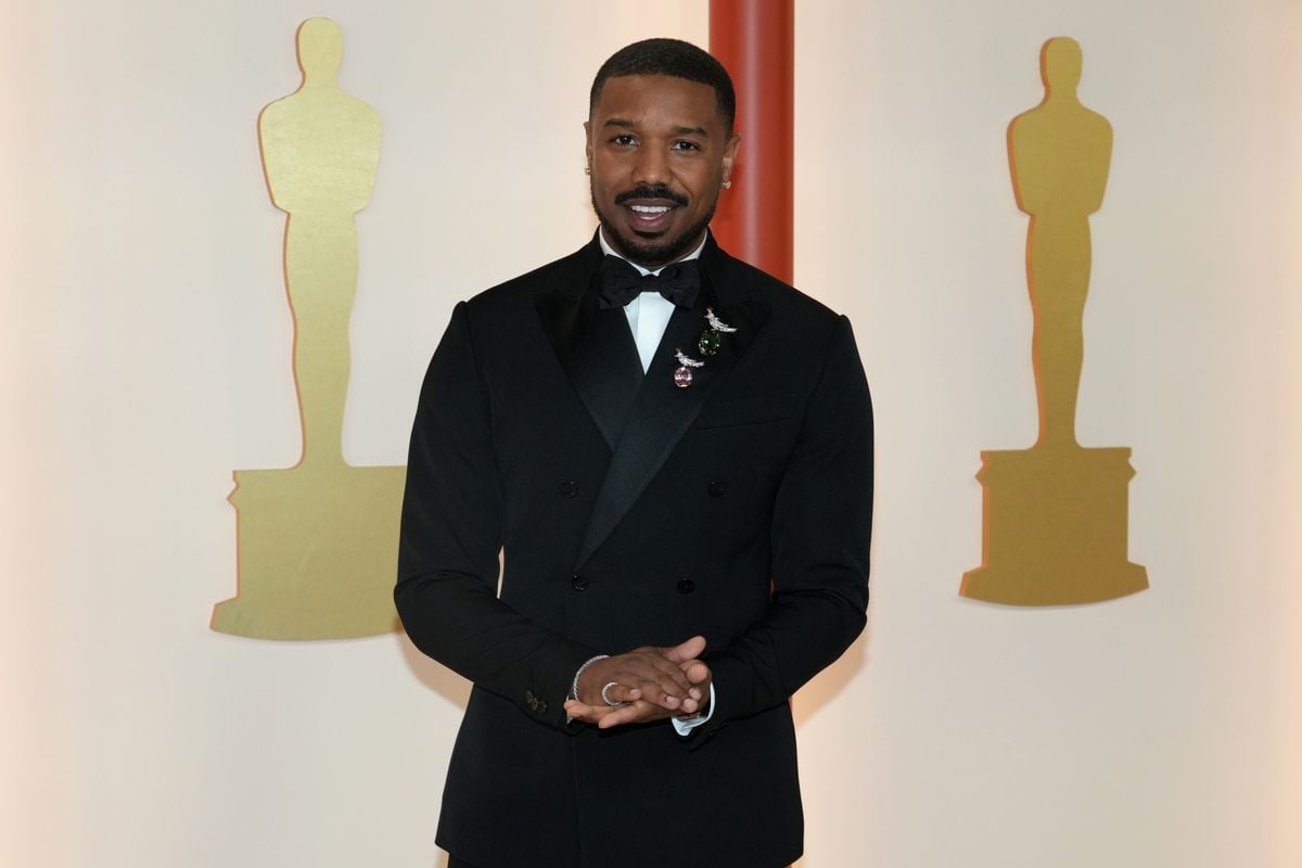 Michael B. Jordan poses in front of a backdrop featuring the Oscars logo.