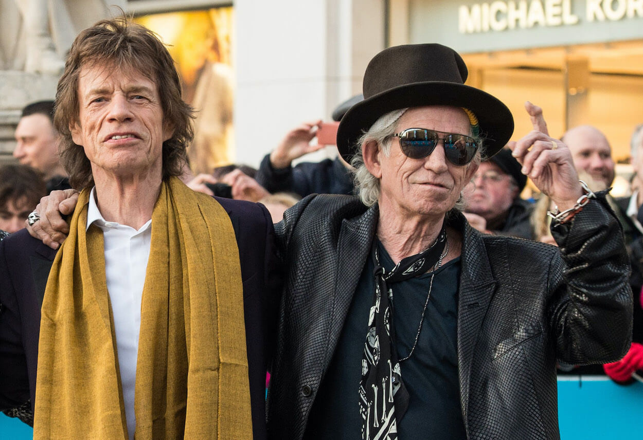 Mick Jagger (left) wears a mustard yellow scarf as Keith Richards wraps his right arm around him during a 2016 event.