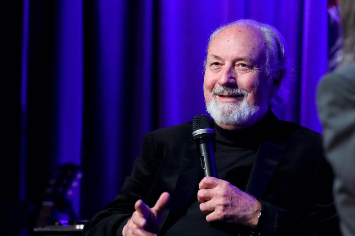 Mike Nesmith smiling, speaking into a microphone