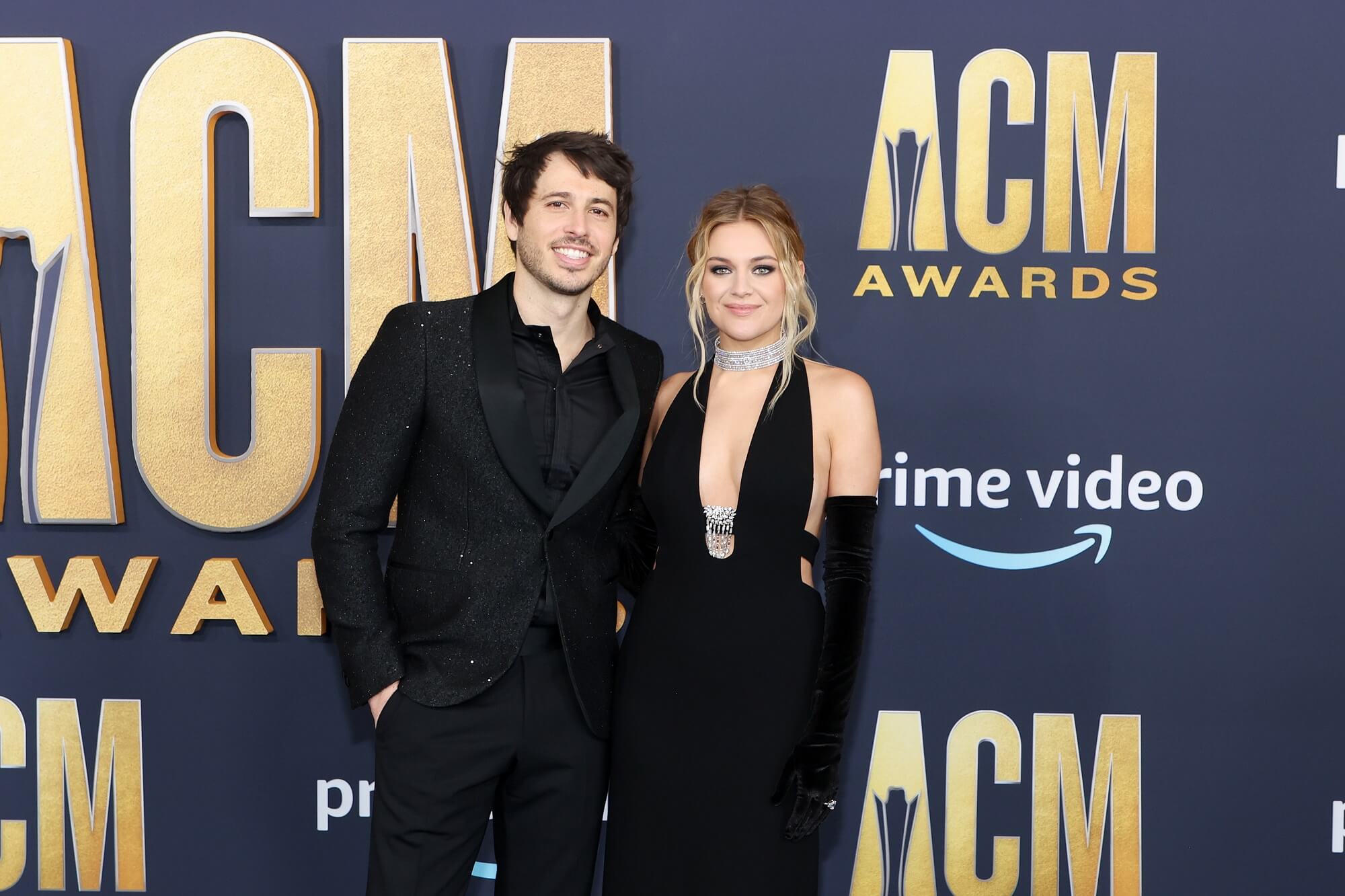 Morgan Evans and Kelsea Ballerini in black outfits in front of a backdrop reading 'ACM Awards'