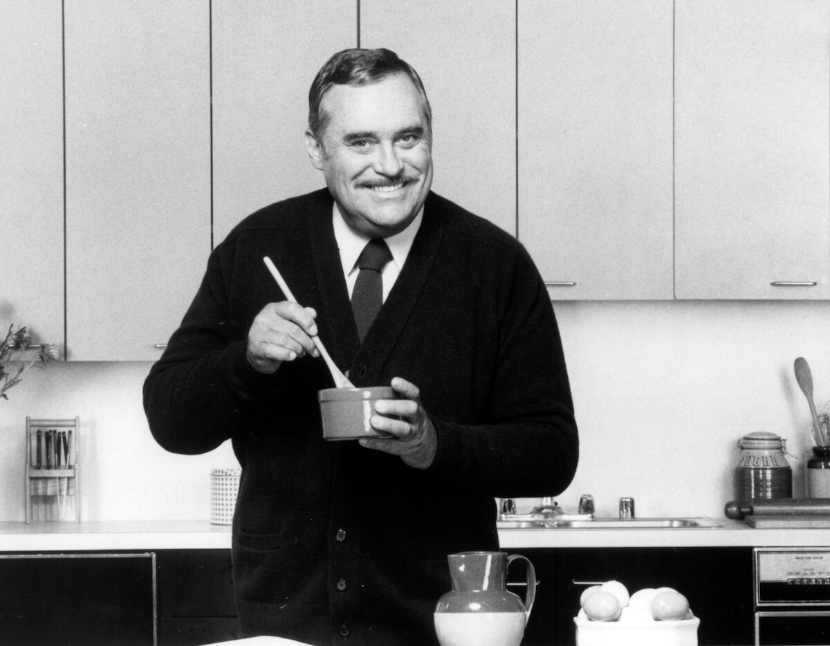 Christopher Hewett in a kitchen stirring something in a bowl in a black and white photo