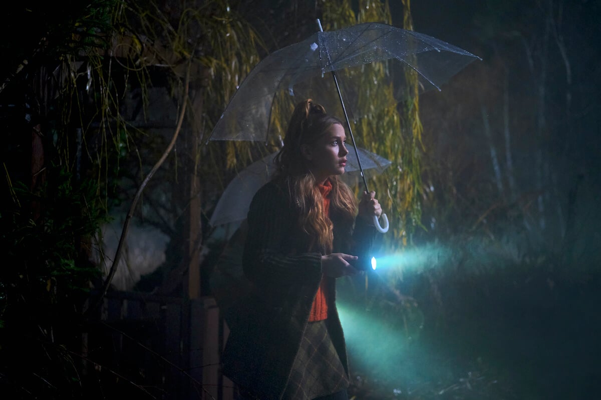 Natasha Bure as young Aurora Teagarden, holding a flashlight, in 'Aurora Teagarden Mysteries: Haunted By Murder'
