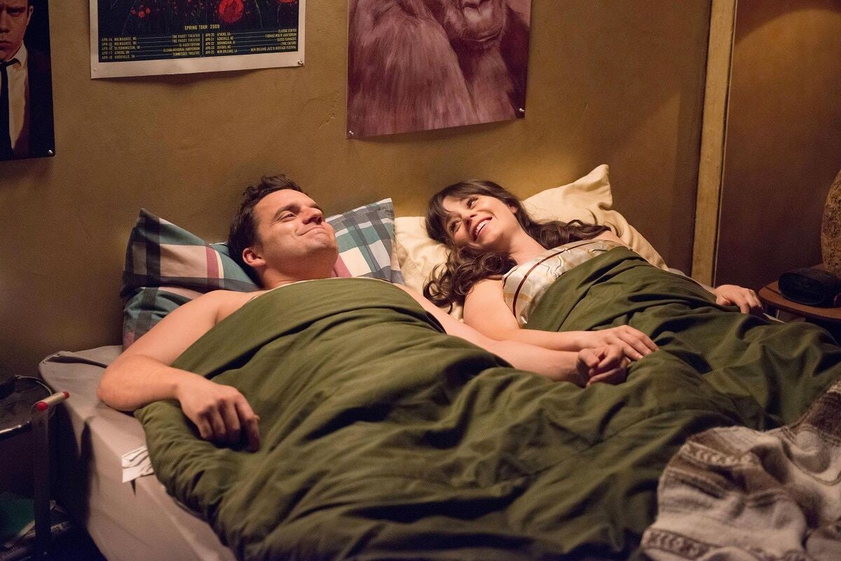 Jake Johnson as Nick Miller and Zooey Deschanel as Jessica Day lay in Nick's bed in an episode of 'New Girl'