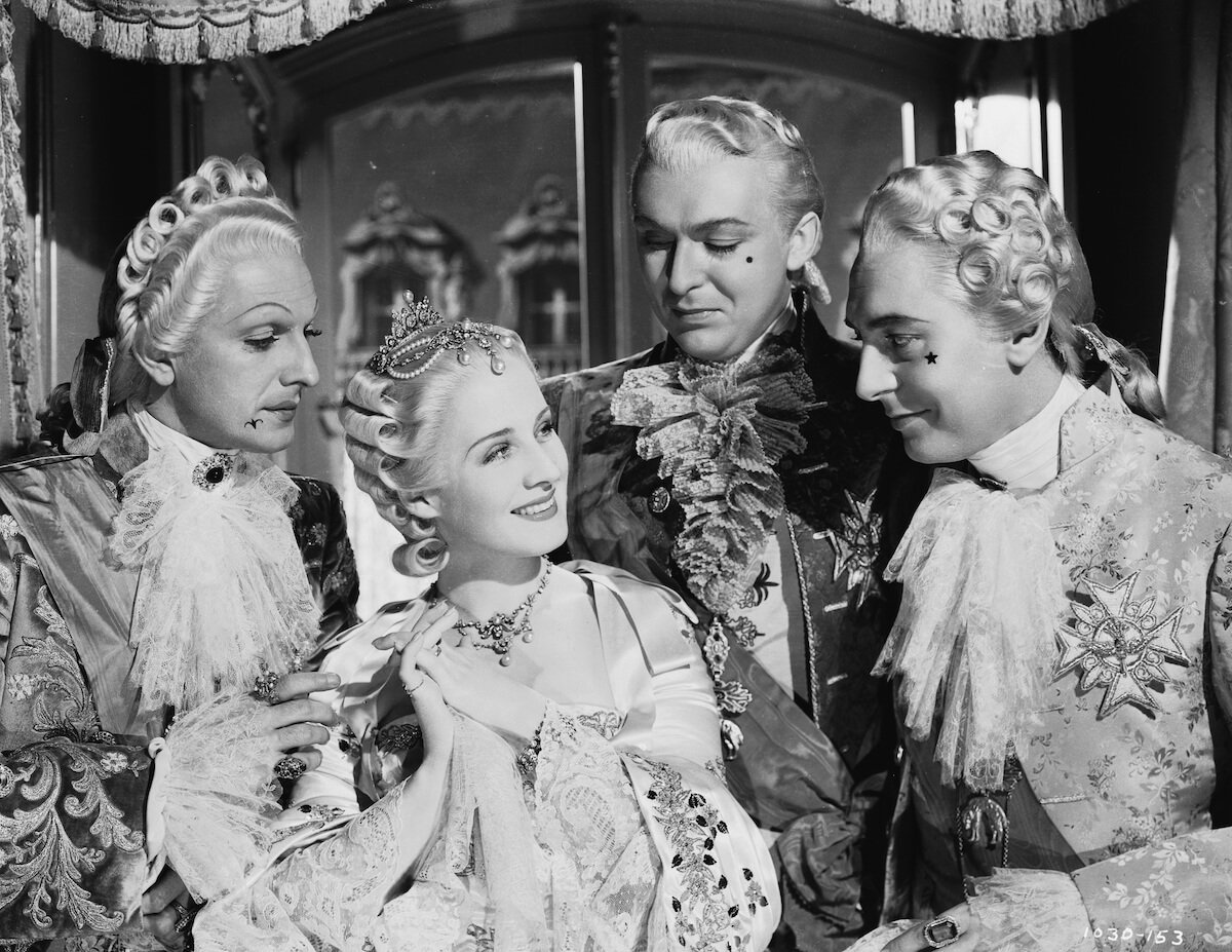 Black and white photo of Norma Shearer surrounded by French courtiers in the 1938 movie 'Marie Antoinette'