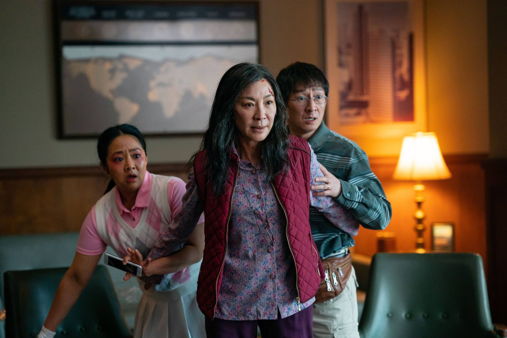 Oscars 2023 Best Picture nominee 'Everything Everywhere All at Once' Stephanie Hsu as Joy Wang, Michelle Yeoh as Evelyn Wang, and Ke Huy Quan as Waymond Wang. Evelyn is standing in front of Joy and Waymond, with them looking worried.