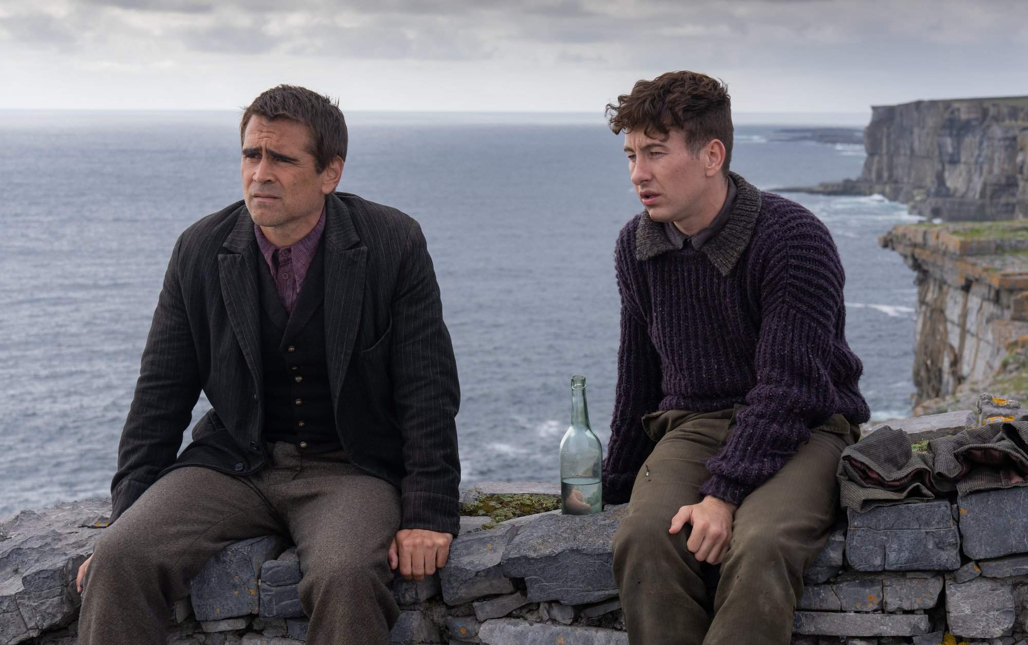 Oscars 2023 Best Picture nominee 'The Banshees of Inisherin' Colin Farrell as Pádraic Súilleabháin and Brendan Gleeson as Colm Doherty sitting on a stone wall with the ocean behind them.
