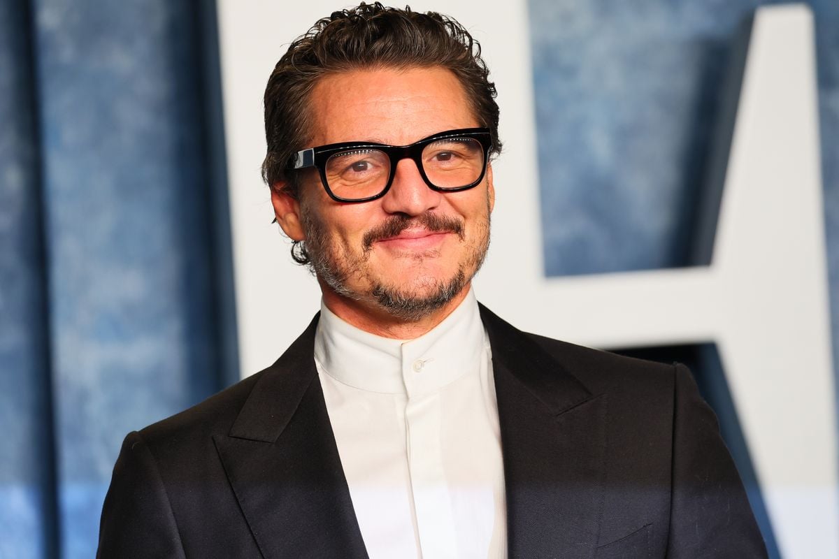 Pedro Pascal poses for a photo in front of a backdrop featuring the Vanity Fair logo.