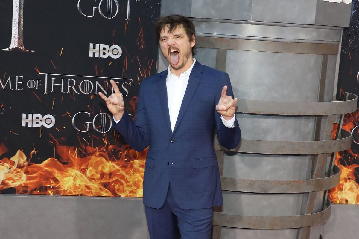 Pedro Pascal poses in front of a backdrop with the "Game of Thrones" logo on it.